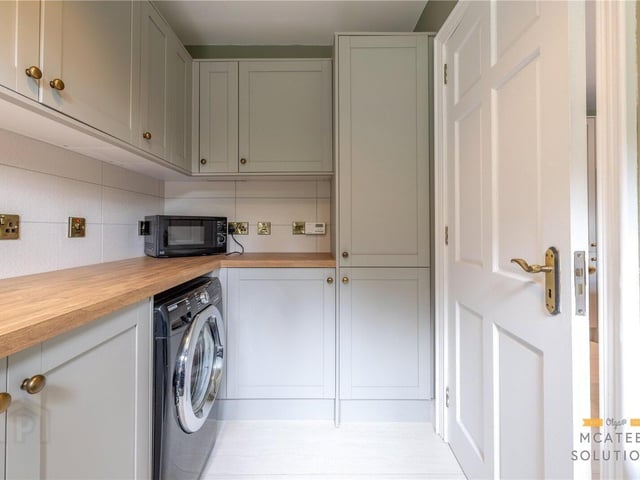 Utility room fitted with low-level units and plumbing for washing machine and tumble dryer.