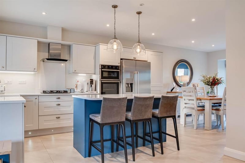 Modern fitted kitchen with integrated appliances and island unit.