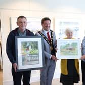 Lisburn resident Marion Hiddleston took first place in the competition for her colourful depiction of the summer house, located within the walled gardens of Rowallane Gardens. 
The second and third places were taken respectively by Lawrence Chambers for his detailed depiction of Lady Alice’s Temple in Hillsborough Castle Gardens and Helen Sara McLarnon for her interpretation of the gardens surrounding Hillsborough Castle. The artists are pictured with then Mayor Scott Carson and Councillor Hazel Legge