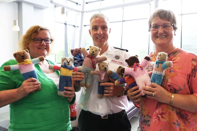 Watch Commander Bryan McCaul with members of Lisburn ‘Knit and Natter’ who contributed to the Trauma Teddies project. Pic credit: NIFRS