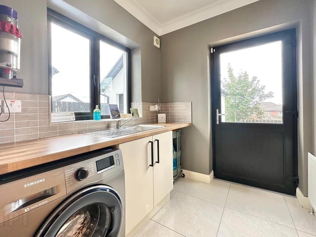 Utility room fitted with a range of low level units with complimentary worktops, stainless steel sink and drainer unit, walls part tiled and plumbed for utilities.