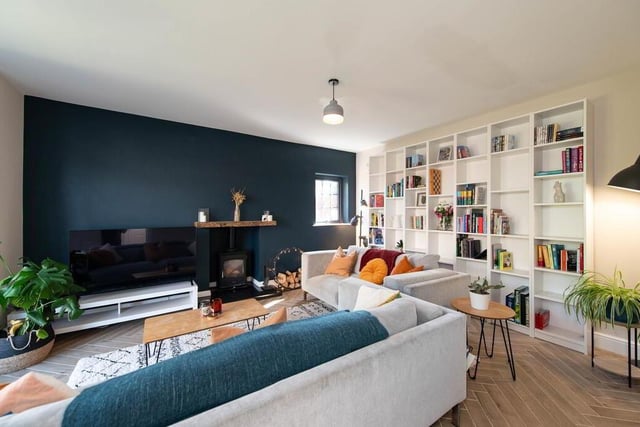 Lounge with parquet tiled flooring, wood burning stove, and feature mantle.