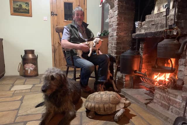 Tandragee farmer Kenny Gracey relaxes in front of the fire with just some of the many animals on his farm. Kenny will feature in the new BBC NI series The Chronicles Of Armagh. Picture: BBC
