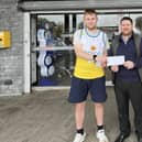 ​Conor Doherty is presented with sponsorship for his running shoes by Paul McArdle, manager of Campbell’s Eurospar, Scarva Street.