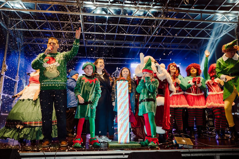Presenter Stuart Robinson, the Deputy Mayor, Councillor Rosie Kinnear, Santa and his elves and competition winner Emma McAlister turn on the Glengormley Christmas tree lights
