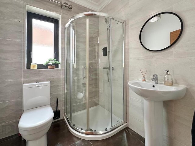 Shower room with contemporary three piece white suite comprising of WC, wash hand basin and vanity unit.