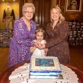It's not a party without a cake and pictured cutting the 65th anniversary cake are, Mrs Elizabeth Quigg, former Guide captain, Lana, youngest member of the group and Zoe Smyth, Brownie leader. LM06-216.