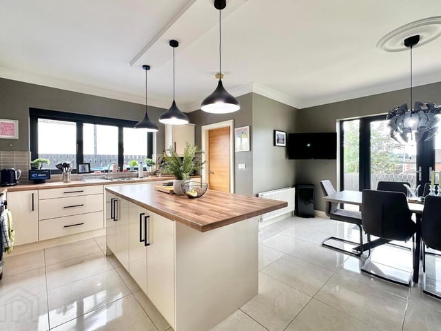 Open plan kitchen/dining area with an excellent range of modern fitted units, stainless steel sink and drainer unit, a large centre island with commentary worktops and splashback tiling. Dining area and fitted patio doors opening directly onto the rear paved patio area.