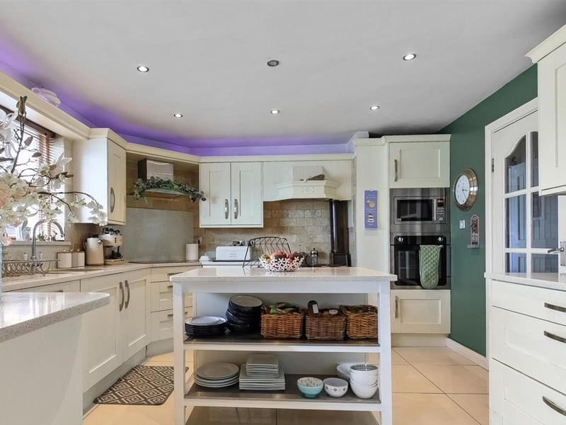 Modern fitted kitchen with range of high and low level storage units with contrasting solid quartz work surface.