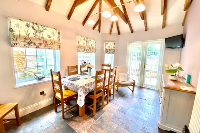 A vaulted ceiling with exposed beams, quarry slate floor and French doors leading to the rear of the property are eye-catching features of the breakfast room.