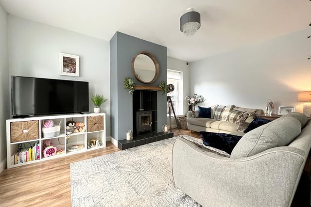 The living room has a wood burning stove with tiled hearth and has been finished with a laminate wood floor.