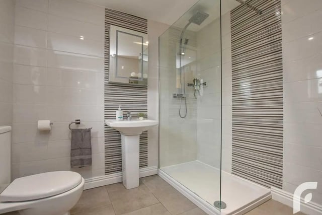 Bathroom with contemporary white three-piece suite including walk in shower, wash hand basin with mirrored Smart Cabinet and low flush WC.