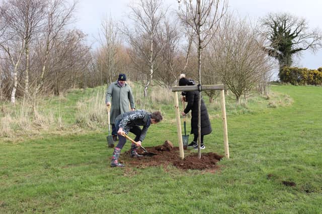 Maternity Ward Sister Katherine Robinson assisting John and Amy McCalister with planting the tree dedicated to her colleague Hazel.