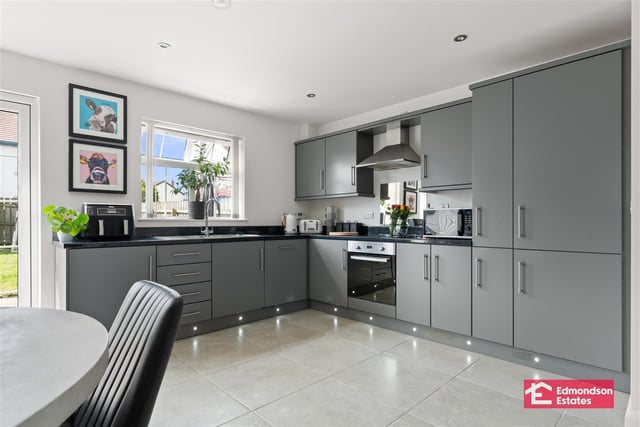 Modern fitted kitchen with high and low level storage units and contrasting work surfaces. Matching upstands. Integrated appliances to include fridge freezer, dishwasher, oven and four-ring electric hob, and stainless steel extractor fan over.