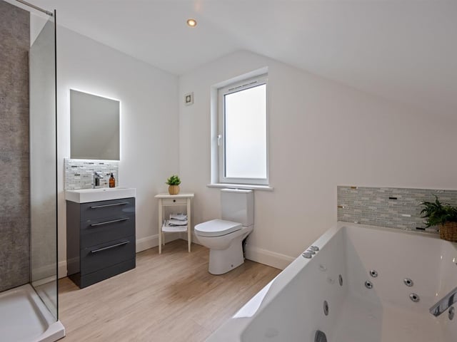 Family bathroom with contemporary, white, four piece suite comprising whirlpool bath, separate oversized shower enclosure, vanity unit and WC.