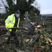 A farmer moves branches and debris from a tree that fell into the graveyard at St Josephs Church on January 22, 2024 in Glenavy, Northern Ireland. Much of the UK was battered overnight by Storm Isha and its high winds, which in some places reached 99mph. (Photo by Charles McQuillan/Getty Images)
