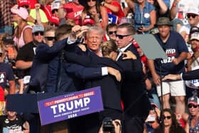 Republican candidate Donald Trump is surrounded by secret service agents as he is taken off the stage at a campaign event in Butler, Pennsylvania after an apparent assassination attempt. Picture: Rebecca Droke / AFP  via Getty Images.
