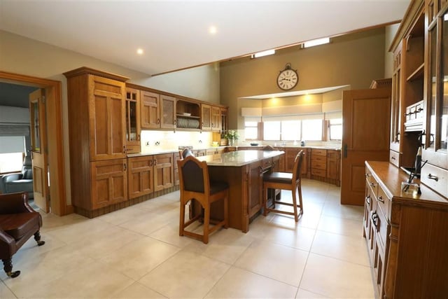 The open plan kitchen / living area with large range of solid oak high and low level units with glass display cabinets, matching dresser, large centre island / breakfast bar with ample storage space and beveled edge granite worktops.