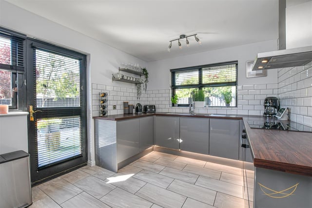 Fitted kitchen with range of high and low high gloss units with contrasting wood worktops. Access to rear garden.