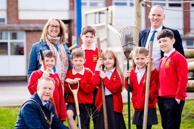 Ald Stephen Ross helps pupils and staff at Carnmoney Primary School to plant their tree.