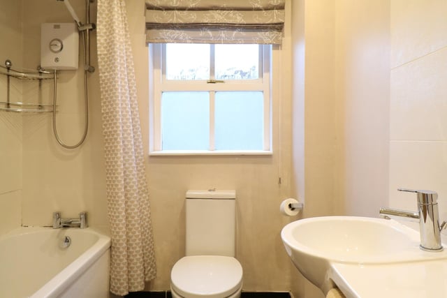 The white three piece suite comprises of a panelled bath, floating wash hand basin and WC, eletric shower unit and mixer tap over bath. There is splashback tiling to the bath and wash hand basin. There is also a chrome towel radiator and tiled floor.