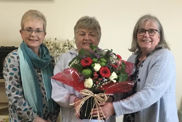 Joan Erwin (centre) receives a bouquet of flowers from Larne Foodbank colleagues Joan Hegarty (left) and Catherine Lynas.