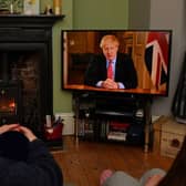 Members of a family listen as Britain's Prime Minister Boris Johnson makes a televised address to the nation from inside 10 Downing Street with the latest instructions to stay at home to help contain the Covid-19 pandemic (Photo: PAUL ELLIS/AFP via Getty Images)