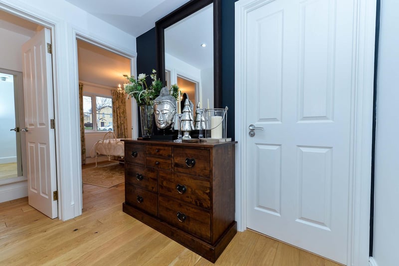 The entrance hall has built in shelved storage cupboards, recessed spot lights, and a solid wood strip floor.