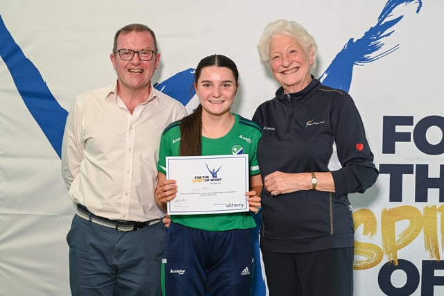 Ballygally hockey player Isla Allen receiving her award certificate from Barry Funston and Lady Mary Peters. Photo submitted by Mary Peters Trust