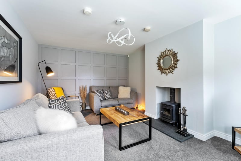 The welcoming front aspect reception room whiich has a wood-burning stove with slate hearth and feature wall panelling.