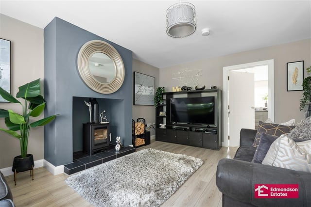 Lounge with wood laminate floor covering and focal point wood-burning stove in Inglenook style recess.