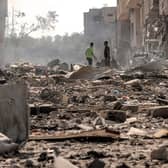 Men stand through debris and destruction littering a street in the Jabalia camp for Palestinian refugees in Gaza City. Photo by MAHMUD HAMS/AFP via Getty Images