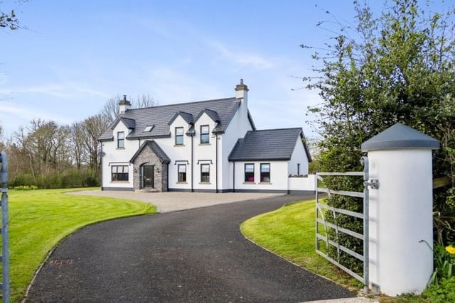 The property is approached through a gated entrance leading to a sweeping driveway flanked by generous lawned areas, rear patio and double garage.