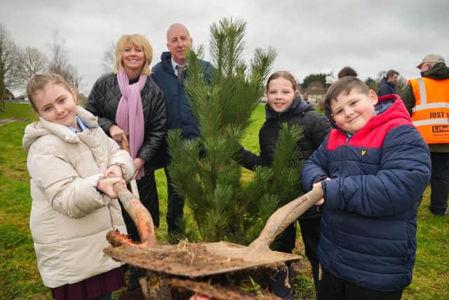 Housing Executive staff dig in with schoolchildren planting trees to improve their community.