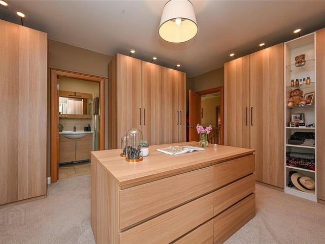 Spacious double bedroom with luxury carpet flooring, currently being utilised as a dressing room with bespoke (non-fixed) modular furniture and en-suite shower room.