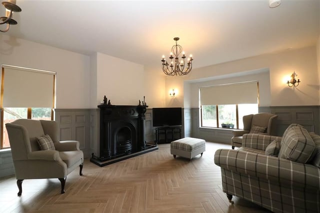 The stylish lounge has a cast iron fireplace with granite hearth and fender, bay window,  under loor heating, tiled floor, chandelier and three matching wall lights and feature wall panelling.