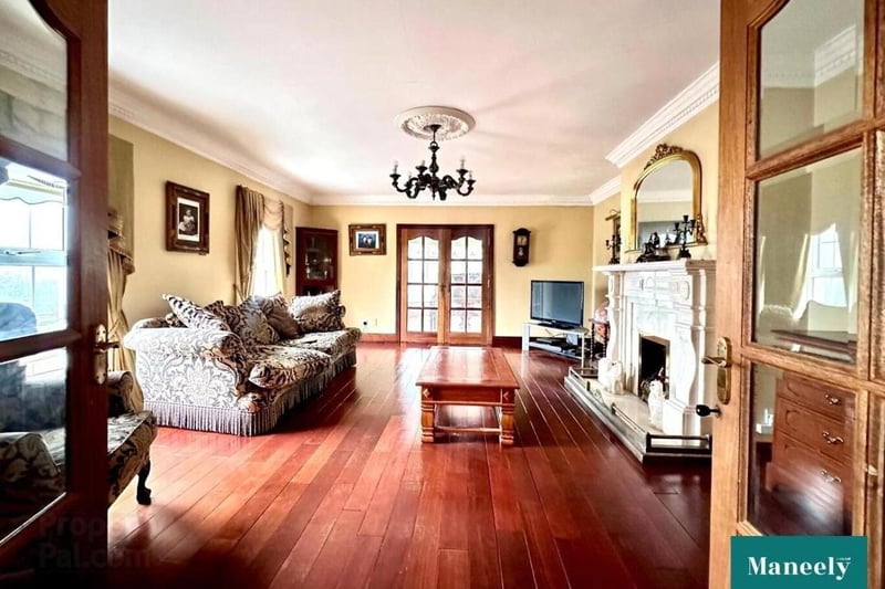 Drawing room featuring gas fire with marble fireplace surround, solid wooden floor, and French doors leading to sunroom.