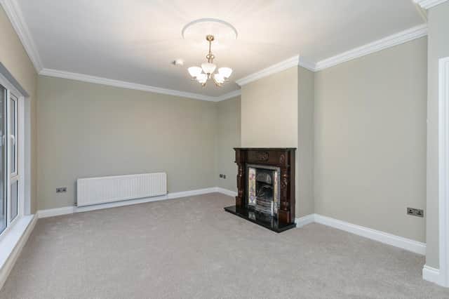 The spacious living room  has a eature fireplace, carpet flooring and cornicing.