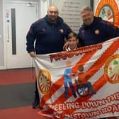 Teenager Kingston Bryars showing off his 'Wheeling down the Brownstown Road' banner to Portadown manager Niall Currie (right) and assistant boss Clifford Adams. Photo by Kingston Bryars.