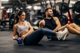 Man and woman working out in a gym using weights.