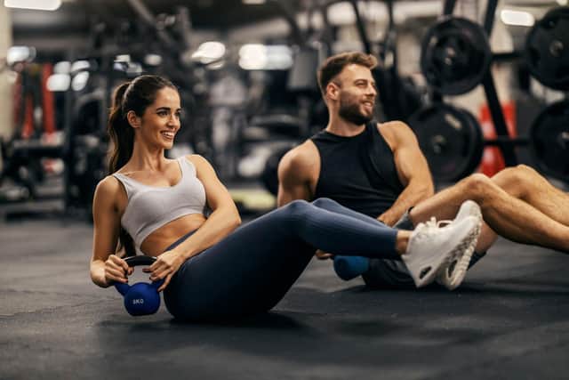 Man and woman working out in a gym using weights.