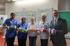 Senior Funeral Director Terry Weir and Dunmurry Crochet Club member Helen Walsh present 10 handmade twiddle muffs to staff at Meadowlands 2, Musgrave Park Hospital, to celebrate the club's tenth anniversary. Pic credit: Terry Weir