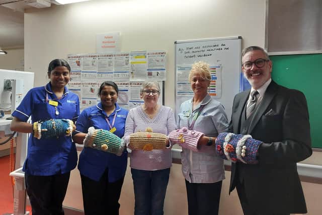 Senior Funeral Director Terry Weir and Dunmurry Crochet Club member Helen Walsh present 10 handmade twiddle muffs to staff at Meadowlands 2, Musgrave Park Hospital, to celebrate the club's tenth anniversary. Pic credit: Terry Weir