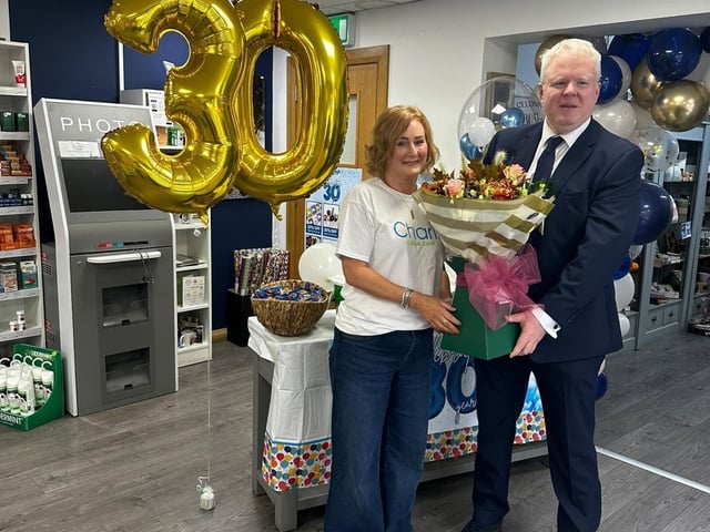 Kathryn Allen receiving flowers from John O’Brien for 30 years service, working in Coagh Pharmacy since its opening.