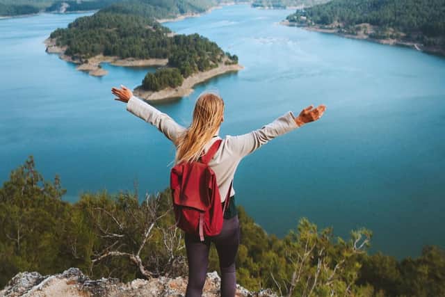 Woman hiker with raised hands enjoying Karacaoren lake view travel outdoor in Turkey.