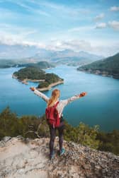 Woman hiker with raised hands enjoying Karacaoren lake view travel outdoor in Turkey.