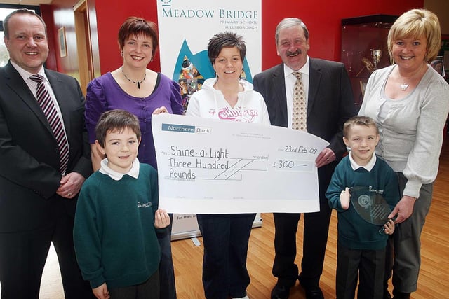 Jennifer McBratney Chair of Meadow Bridge PTA, Leigh-Ann Dillon Meadow Bridge PTA and Paul Good Meadow Bridge Primary School Principal  presented a cheque for £300 to Billy McCrory of Shine A Light in 2009. The money was raised through Bag Packing at Sainsbury's at Christmas Time also pictured are Curtis Girvan, Gaye Kerr and Brian Kerr from Shine A Light