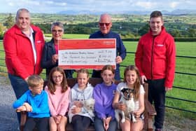 Bill Ferris, alongside his wife Linda and their grandchildren, presenting a cheque for £1,250 to Air Ambulance NI volunteers Derek and Madison.