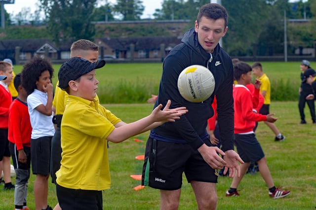 One of the Healthy Kidz coaches teaches the Gaelic football fist pass during the joint fun day. PT24-215.