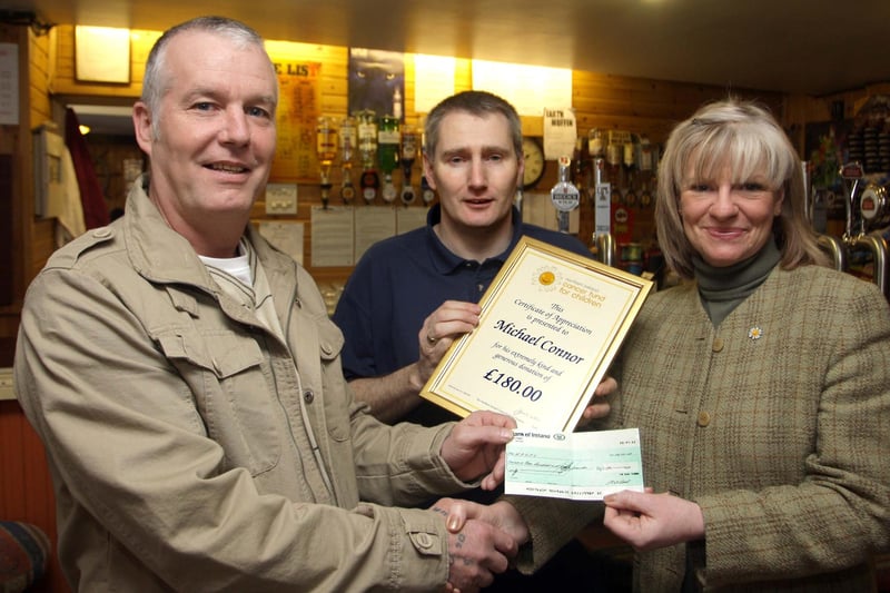 Mickey Connor (left), who organised a Quiz Night back in 2010 to raise funds for the N.Ireland Cancer Fund for Children, pictured handing over the proceeds - a cheque for £180.00 - to Gillian Creevy on Friday. Looking on is Craig Black, owner of the Bush Tavern where the quiz took place, who is also holding a framed certificate which was presented to Mickey from Gillian in recognition of his fundraising. For the record, Mickey raised around £12,000 for the charity since 2004.